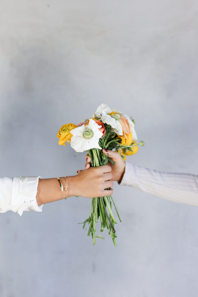 Close-up of two hands gently holding a bouquet of fresh flowers, symbolizing growth, connection, and the flourishing of a Kingdom-hearted business.