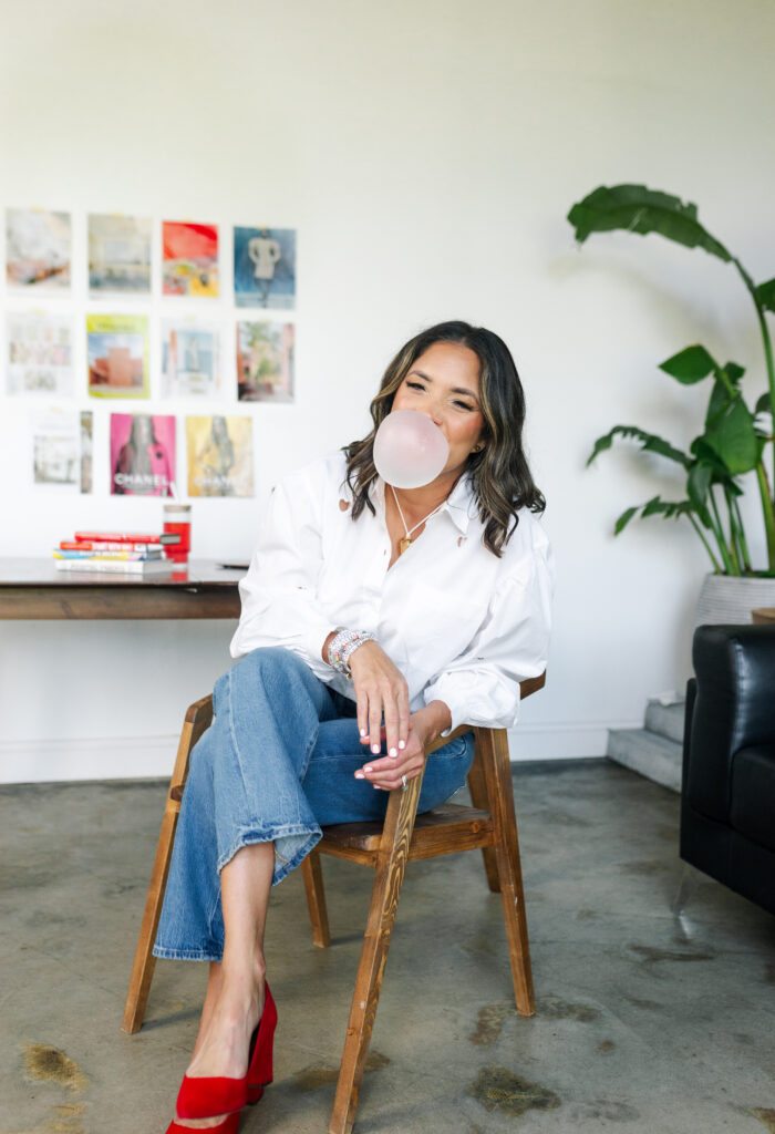 Candid photo of Desiree Hayes casually laughing and blowing bubble gum, showcasing a playful yet editorial side of her personality for women entrepreneurs seeking inspiration and connection.